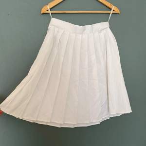 Vit plisserad kjol, ursprungligen från Kappahl. Lite skrynklig för tillfället men i fint skick! Knäppning med dragkedja och knapp i sidan. Storlek 40 men passar mer som 38. 