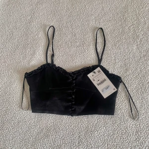 ZARA svart croptop med knappar och volangkant - Snygg croptop från ZARA med volangkant och knappar. Stretchig rygg. Ny med tags kvar, utan anmärkningar.