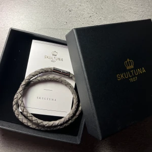 Skultuna läderarmband  - Säljer ett Suede Braclet - Grey från skultuna. Nypris 1500 kr. Fick det i present men har haft det för länge för att kunna returnera. Helt i ny skick och har aldrig burits utomhus.