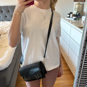 Axelremsväska  - Säljer denna snygga axelremsväska från glitter då den inte har använts. Använd max en gång och är i bra skick. Tillkommer också med ett annat band som är tjockare som är samma mönster som väskan. Pris: 175kr + frakt 