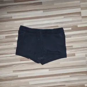 Ett par svarta shorts med elastisk midja och dragsko. Shortsen är tillverkade i ett mjukt material. Från H&M i storlek 134