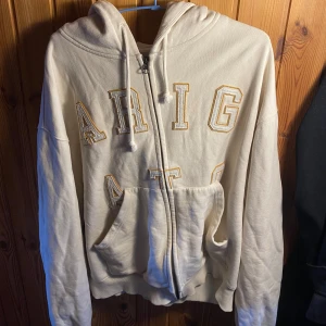 Arigato Legend Zip Hoodie - Beige Arigato Zip Hoodie, äldre modell men fortfarande mycket liv i sig. 8/10 Cond, inga hål eller fläckar. Strl L men det är oversized och cropped.