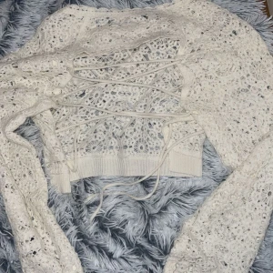 Tröja  - En stickad tröja som är genomskinlig och öppen på ryggen, man kan styra hur tajt trojan ska sitta