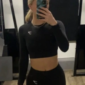 Gymshark träningstopp  - Storlek XS. Sparsamt använd då jag inte tycker om att träna i långärmat. Mycket gott skick. Finns även tumgrepp vid ärmmudden på tröjan. 
