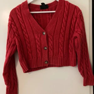 Stickad kofta - Röd stickad kofta i gott skick. Köpt på second hand, insåg då att den blivit krympt i tvätten sedan innan och därför inte passade. Kanske passar någon annan☺️