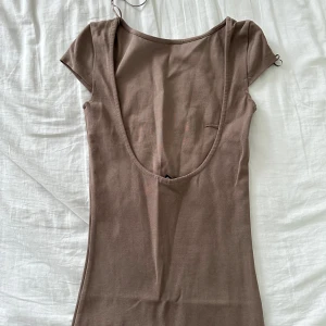 Lång klänning med djup rygg gina - Lång mörkbeige klänning med djup rygg från Gina tricot använd 1 gång. Super snygg på 