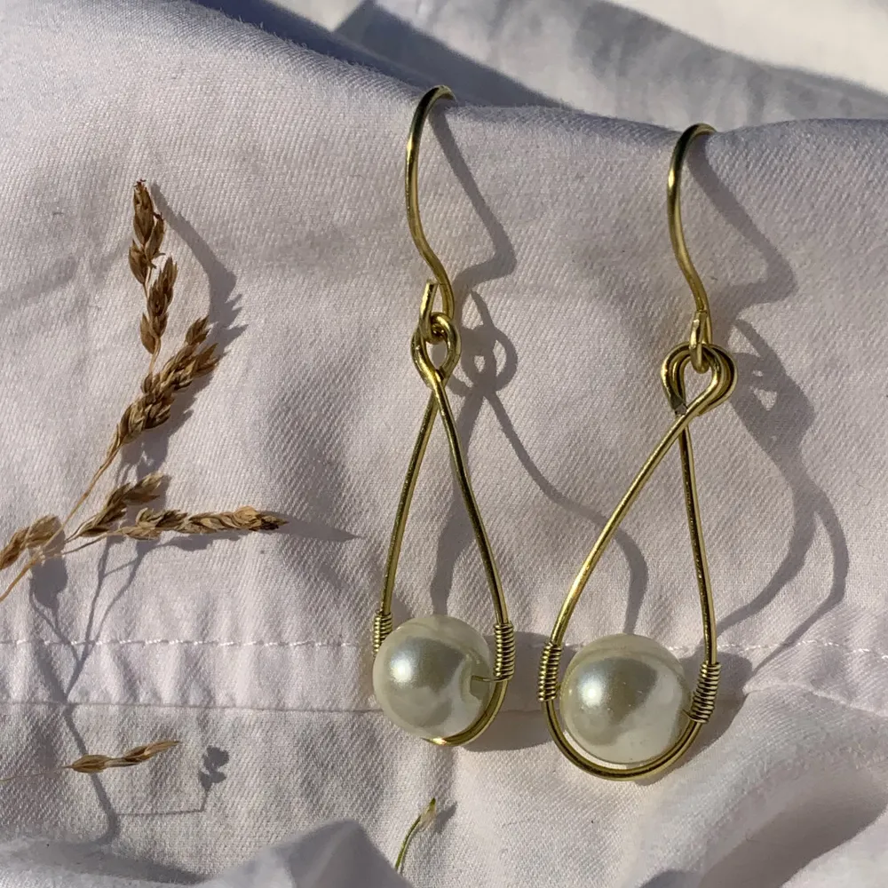 Handgjorda örhängen med offwhite pärlor, och guldpläterad koppartråd. Nickel-, kadium- och blyfria. 3,5x1,5cm. Accessoarer.