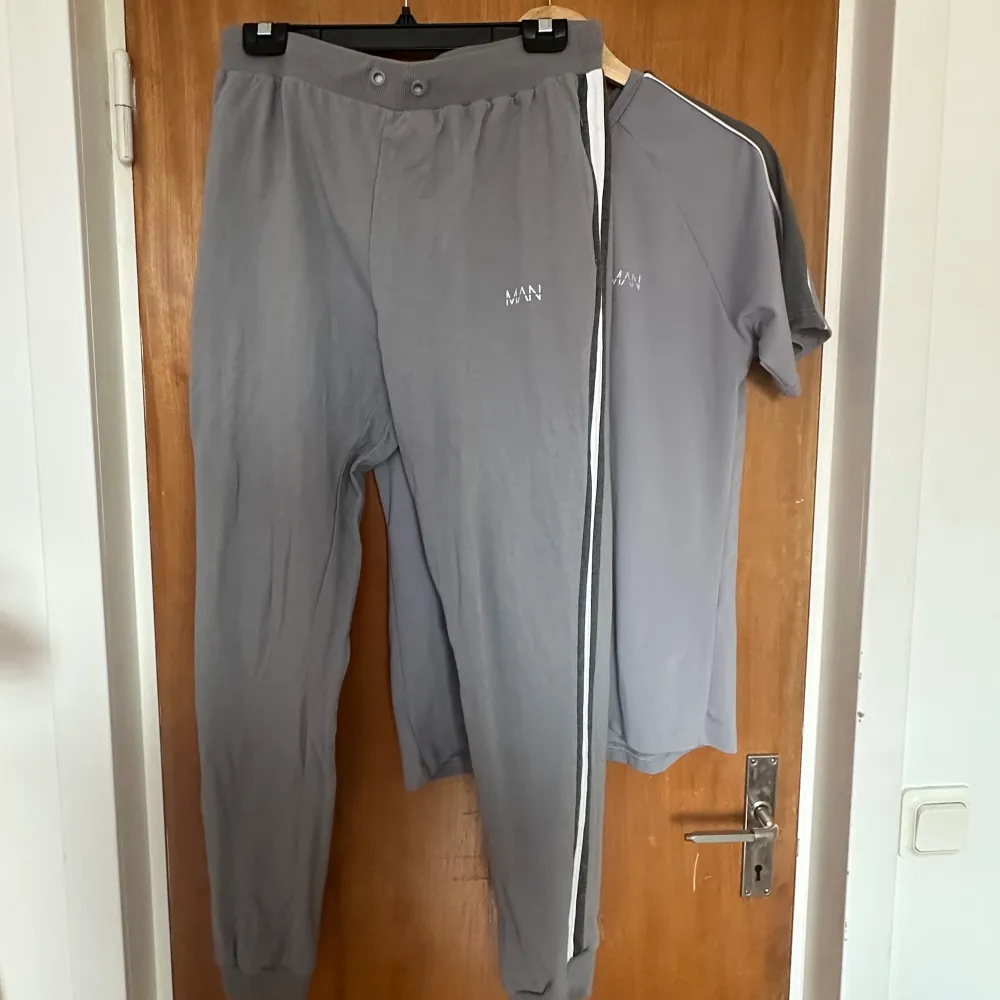 Ett par gråa joggingbyxor från MAN, samt en T-shirt från samma märke. Storlek L i byxorna och M i tröjan. Hoodies.
