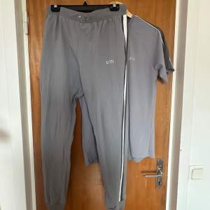 Ett par gråa joggingbyxor från MAN, samt en T-shirt från samma märke. Storlek L i byxorna och M i tröjan
