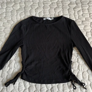 Topp med knytdetalj - Långärmad topp med knytdetalj på sidorna från Na-kd.