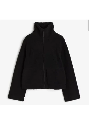 Svart teddyjacka med dragkedja - Mysig svart teddyjacka med dragkedja framtill. Jackan har en klassisk, enkel design och är perfekt för att hålla värmen. Passformen är normal och materialet är fluffigt och mjukt. 