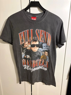 Grå Full Send Hasbulla t-shirt - Grå t-shirt från Full Send med stort tryck av Hasbulla och text i rött och vitt framtill. Klassisk passform med rund hals och korta ärmar. Perfekt statement-plagg för dig som gillar streetwear och unika prints.