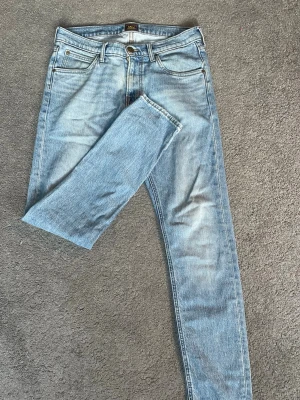 Ljusblå raka jeans från Lee - Snygga ljusblå jeans från Lee med klassisk femficksdesign och raka ben. Jeansen har en vintage tvätt och detaljer i mässing. Perfekta för en avslappnad och trendig stil.