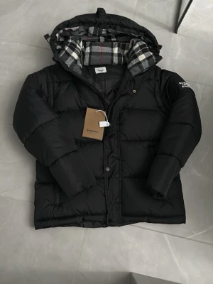 Puff jacka från Burberry - Snygg svart pufferjacka från burberry. Jackan har dragkedja och knappar framtill jackan är även väldigt varm. Även av tag bara armar Perfekt för kalla dagar och riktigt trendig stil. Pris är ej hugget i sten och kontakta vid frågor!