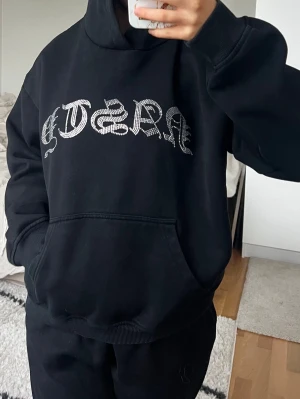 Hidden Cult  - Svart Hidden Cult huvtröja. Storlek M i fint skick. På framsidan finns en stor strassdekor med texten 'NASTY' i gotisk stil. Tröjan har en loose passform och är tillverkad i mjukt bomullsmaterial, perfekt för chill dagar. Har även tillhörande mjukisbyxor i en annan annons 🖤