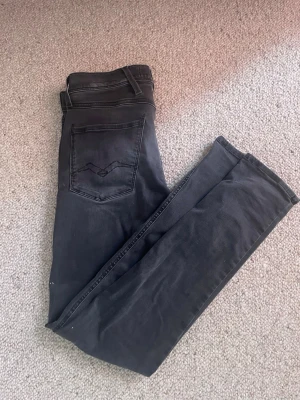 Replay Anbass Jeans - Stilrena Replay Anbass Slim jeans i mörk tvätt. Slim fit-modell som sitter snyggt utan att kännas för tight. Jeansen är i mycket fint skick och ser knappt använda ut. Perfekta både till vardag och lite mer uppklädda outfits.