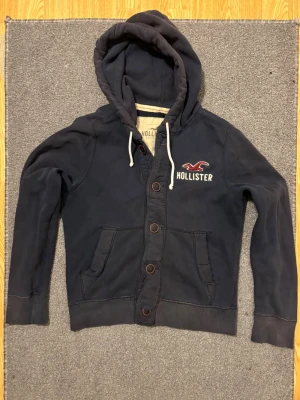 Vintage Hollister Cardigan Med Knappar - Säljer denna otroliga sällsynta och feta Hollister cardigan med knappar | Bra skick, urtvättad färg | Längd ≈ 61cm, Bredd armhåla - armhåla 51 cm | Modell 175, 68 kg