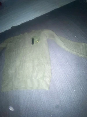 Olivgrön stickad tröja Lyle & Scott - Säljer en olivgrön stickad tröja från Lyle & Scott med ribbstickad struktur och en bröstficka med lock och den klassiska gula loggan. Tröjan har långa ärmar och rund hals, perfekt för dig som gillar stilrena och bekväma plagg.