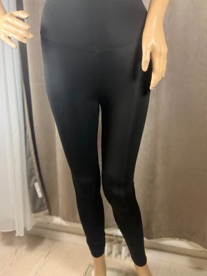 Svarta höga leggings i stretch - Svarta leggings med hög midja och tight passform. Tillverkade i ett stretchigt material som sitter skönt mot kroppen. Perfekta att matcha med oversized tröjor eller hoodies. Klassisk och enkel design utan synliga loggor eller detaljer.