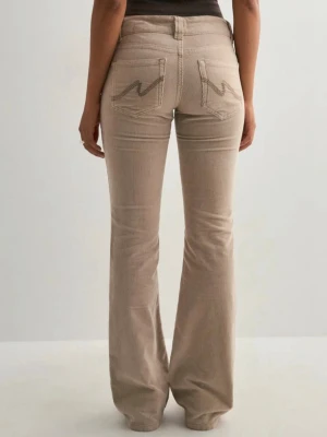 Beige bootcut manchesterbyxor - Snygga beige manchesterbyxor med bootcut-passform och låg midja. Byxorna har klassiska fickor fram och bak, med coola broderade detaljer på bakfickorna. Helt nya i original förpackning💖.