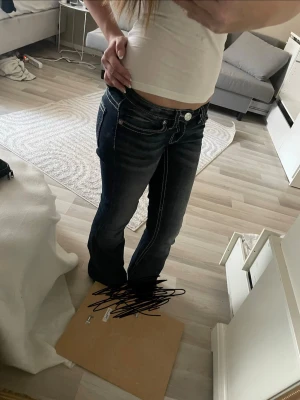 Mörkblå bootcut jeans med brodyr - Säljer ett par mörkblå bootcut jeans klippt där nere