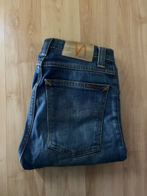 Nudie jeans  - Jeans från Nudie Jeans, modellen High Kai. Midja 32cm, längd 98cm. Obs jeansen är uppsydda, jag skulle bedöma dem till L30, men utgå efter mått. Jensen har blivit lagade i skrevet & vid en bälteshällen men fungerar precis som vanligt - se närbild. JAG SKICKAR EJ FLER BILDER NÄR JAG BÄR JEANSEN! för bättre inblick i passformen rekommenderar jag att googla på modellnamnet. För storleksguide kolla måtten noggrant då jeansen alltid kan vara uppsydda heller krympta och jag ej tar emot returer :) s6,4