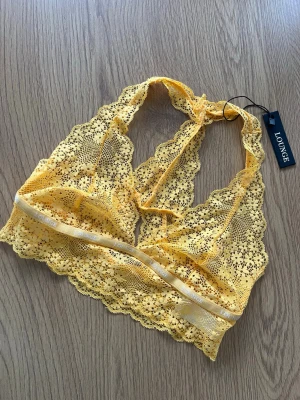 Gul spetsbralette från Lounge - Säljer en ny senapsgul topp från Lounge Underwear. Toppen är ärmlös och har vackra blommiga spetsdetaljer samt elastiskt band under bysten. Modell Floral Lace Triangle Bralette. Storlek S 💛