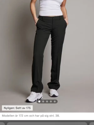 Lågmidjade svarta kostymbyxor från bikbok Vera i tall - Svarta lågmidjade bootcut kostymbyxor från bikbok i modellen Vera. Dem är pyttelite insydda i midjan men syns ej skickar bild och mått om ni vill ha. Bra skick men något noppriga hör och där och pyttelite slitna längts ner men syns ej. Dem är i storlek 36 tall 