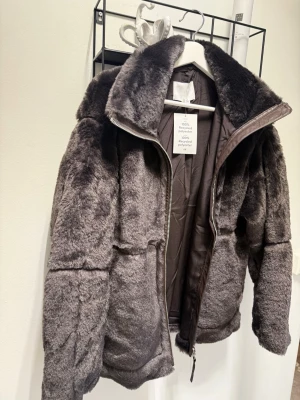 Brun teddyjacka från H&M -  Helt ny Mysig brun pälsjacka  från H&M i 100% återvunnen polyester. Jackan har en hög krage, dragkedja framtill och är fodrad för extra värme. Perfekt för kalla dagar när du vill vara både snygg och bekväm.Storlek S 