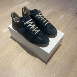 Blåa sneakers från Maison Margiela - Mörkblåa gats ifrån Maison margiela skick 7/10 storlek 43. Pris ej hugget i sten vänligen kontakta om du har några frågor😁