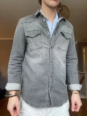 Dondup skjorta – storlek S   - Snygg och stilren skjorta från Dondup i tvättad grå denim-look. Väldigt clean passform och hög kvalitet, funkar både till vardag och mer uppklädda outfits.    Skick: Mycket bra skick, inga fläckar eller hål.   Storlek: S   Färg: Grå    Nypris ca 1500 kr.    Pris: 599 kr  