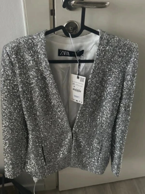 Glittrig silverkavaj från Zara - Säljer en superglittrig silverfärgad kavaj från Zara. 