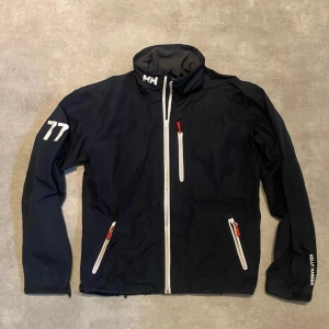 Helly Hansen Jacka - Klassisk HH jacka med mycket detaljer. Storlek L men sitter som en M mer. Gott skick. Perfekt för sommarkvällar! Vid frågor kontakta, allt gott.