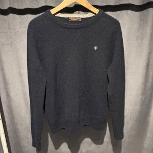 Morris tröja  - Klassisk mörkblå Lambdwool tröja från Morris med rund halsringning och diskret broderad logga på bröstet. Tröjan är tillverkad i mjuk ull och har ribbade muddar vid ärmslut och nederkant. Perfekt för lager på lager och stilrena outfits. Tröjan är i storlek M men passar mer storlek S. Skriv vid minsta fundering! 