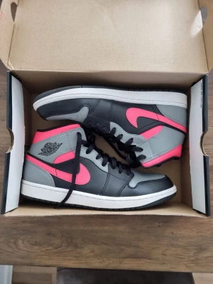 Air Jordan 1 Mid Black/Hot Punch – EU 44.5 – Nyskick - Säljer ett par Air Jordan 1 Mid i färgen Black/Hot Punch/White. Riktigt snygg färgkombination med rosa detaljer som sticker ut. Skorna är i mycket fint skick, knappt använda (se bilder). Kommer med originalkartong.  Obs! (Litet märke finns på skorna, se sista bilden)   Priset kan diskuteras😊  #Nike, #Jordan, #Air Jordan 1, #Jordan 1 Mid, #AJ1, #Sneakers, #Streetwear, #Svart, #Rosa, #nyskick
