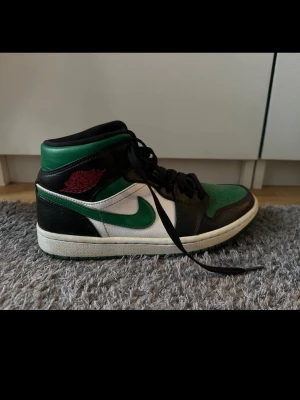 Nike Air Jordan 1 Mid svart/grön/vit - Snygga Nike Air Jordan 1 Mid sneakers i svart, grön och vit med klassisk röd Air Jordan-logga på sidan. 💚I fint skick, strl. 40 men passar mig som har 39 också! Pris kan diskuteras 