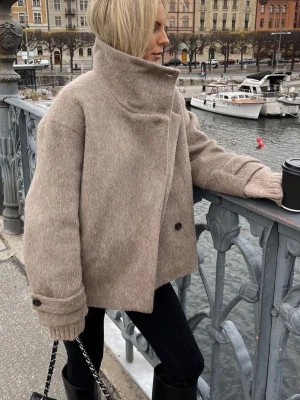 Beige ullkappa arket - Snygg beige jacka i ull med oversized passform och hög krage. Jackan har en dubbelknäppning framtill. Perfekt för nu i vinter eller till våren. Den är knappt använd och i fint skick!