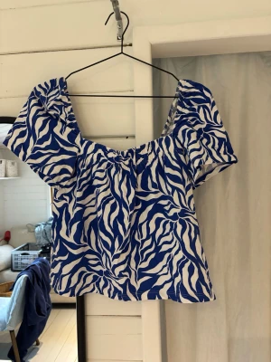 Blåvit mönstrad topp H&M -  blå och vit topp från H&M, korta ärmar, går att välja urrigningen.