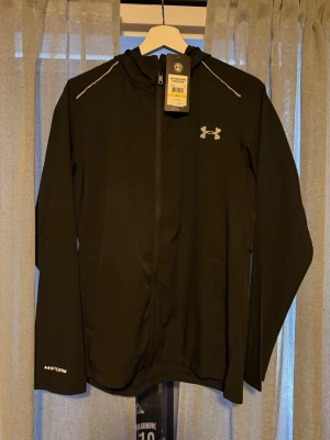 Svart vindjacka från Under Armour - Helt ny Windbreaker från Under Armour. Storlek L och alla tags kvar på den. Tveka inte vid att höra av er!