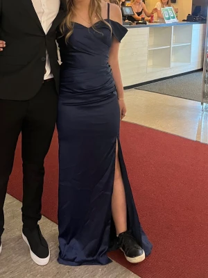 Marinblå långklänning med slits - Intressekoll på min balklänning!                    Elegant marinblå långklänning med offshoulder och smala axelband. Klänningen har en snygg slits framtill och figurnära passform som framhäver siluetten. Perfekt för speciella tillfällen där du vill känna dig extra fin. Endast använd en gång. Kommer inte ihåg vart den är ifrån men köptes online från USA