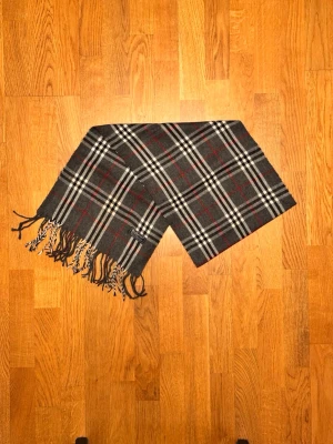 Grå Burberry halsduk - Säljer en grå halsduk från Burberry. Halsduken är i gott skick och är gjord i 100% lamull. Var inte rädd för några frågor. Pris diskuteras inte!