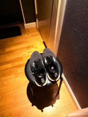 Svarta Adidas sneakers med vit sula - Snygga svarta sneakers från Adidas med vit sula och klassiska ränder på sidan. Ovandelen är i meshmaterial som andas och skorna har snörning. Perfekta för en sportig och avslappnad stil.