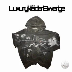 Racer worldwide hoodie - Cool svart hoodie från Racer Worldwide med stort grafiskt tryck av ansikten och logga i rött och grått på framsidan. Klassisk huva och känguruficka framtill. Perfekt för dig som gillar streetwear och unika prints.