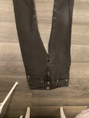 Svarta Lee skinny jeans - Säljer ett par svarta skinny jeans från Lee med klassisk femficksdesign och diskreta sömmar. Jeansen har en smal passform och är tillverkade i stretchigt denimtyg för extra komfort. Perfekta för dig som gillar en stilren look. Nya