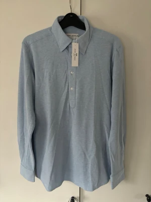 Helt ny oanvänd John Henric skjorta S  - Helt ny oanvänd Ljusblå jättesnygg populär trendig John Henric skjorta i storlek S säljes. Utmärkt skick då den är helt oanvänd med tagen kvar och passar till allt!