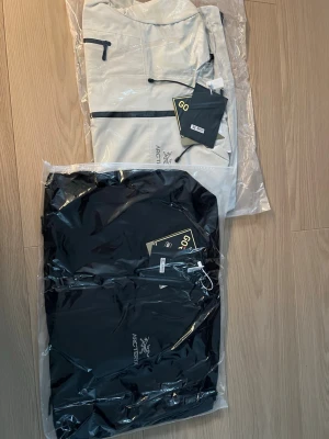 Svart vindjacka med huva  - Helt ny med tags. Vattentålig skaljacka med huva, vattentäta dragkedjor och justeringar. Passar ca 185 cm / runt 90 kg. Perfekt för regnigt väder, vandring, gymnasiet, eller vardag. Jag har själv en likadan som jag använder varje dag – väldigt bra kvalitet och bra mot regn/vind.