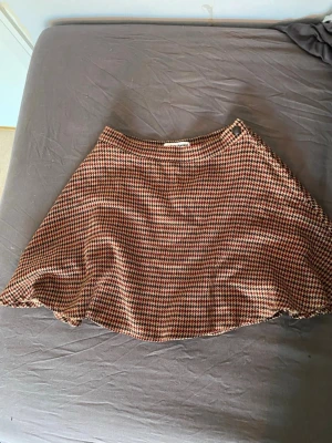 Rutig kortkjol  - Säljer en snygg kortkjol med rutigt mönster i beige, svart och vinrött. 