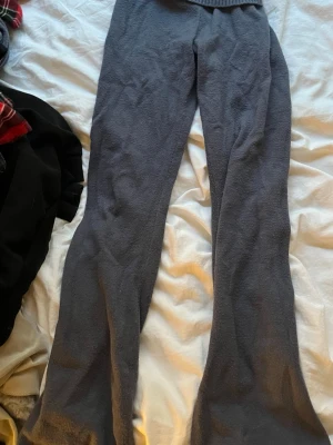 Mörkgrått stickat loungewear-set - Mysigt mörkgrått loungewear-set med vida byxor och matchande hoodie med dragkedja. Setet är stickat i mjukt material och har en croppad tröja med huva och bred ribbad kant. Perfekt för chill dagar hemma eller när du vill vara bekväm men ändå snygg.