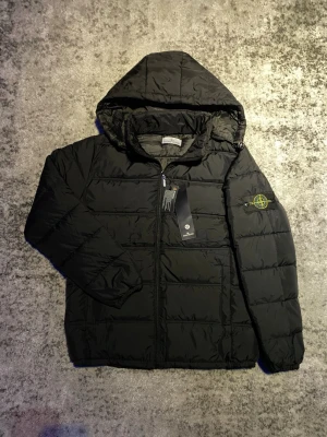 Svart Stone Island jacka - Säljer denna riktigt schyssta Stone Island jacka i mycket bra skick. Jackan är lite tunnare och passar bra till svalare höst/vårdagar. Storleken är M men passar mer som en mindre S, värt att notera är att metallbiten på dragkedjan inte är original. Hör gärna av dig vid funderingar om t.ex. mått, fler bilder eller annat! 😁