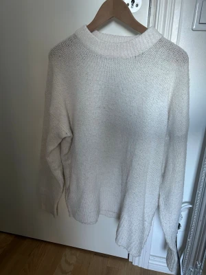 Vit stickad tröja - Mysig vit stickad tröja med avslappnad passform och bred ribbad krage. Tröjan har långa ärmar och är tillverkad i ett mjukt material som passar perfekt för kyligare dagar. Enkel och stilren design som är lätt att matcha. Däremot lite nopprig. Kan sänka priset!!